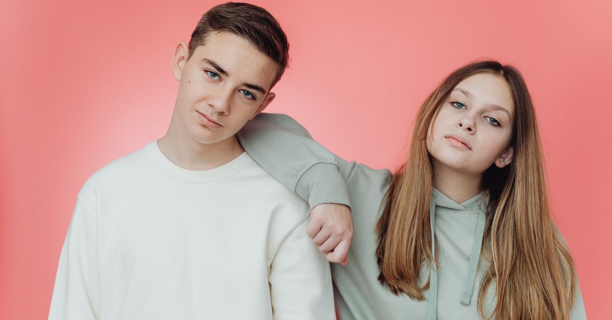 Portrait of stylish teenagers against a pink studio backdrop.